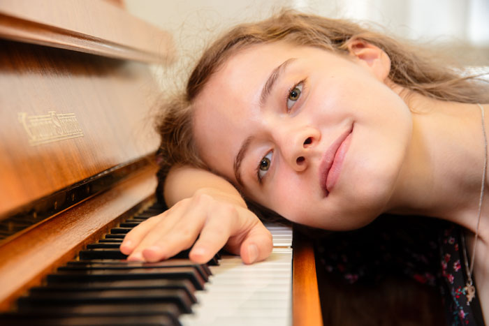 klavierunterricht braunschweig - eine junge frau haelt ihre hand und ihren kopf auf den tasten eines klaviers 442