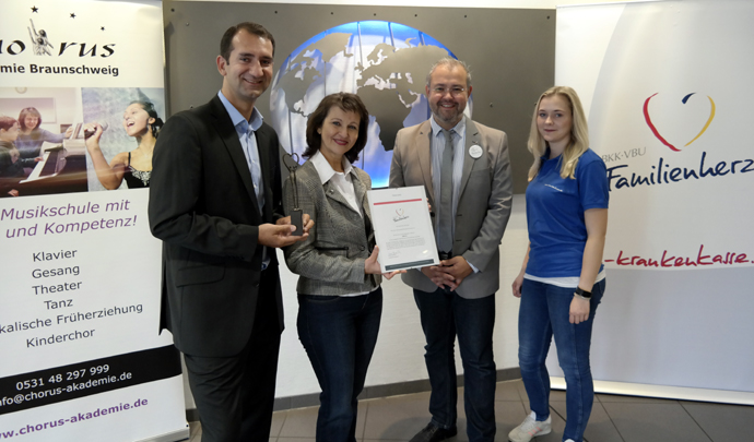 nationaler preis familienherz - vier personen stehen vor zwei bannern und einer Weltkarte aus eisen 162