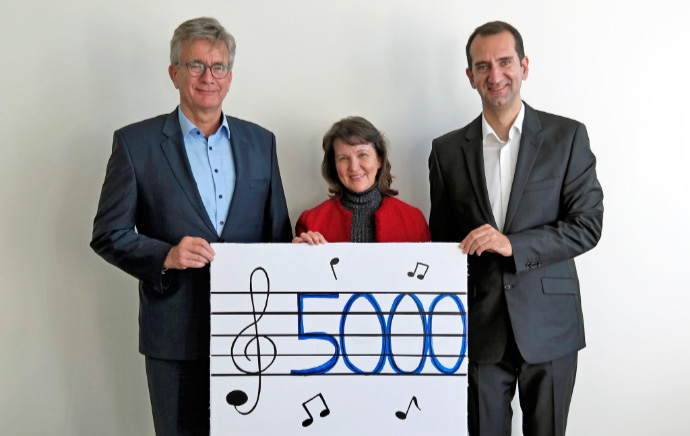 bs-energy - drei personen halten einen check auf dem ein violinenschluessel und die zahl 5000 abgebildet sind